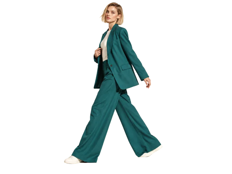Woman in a tailored teal suit walking through a bright studio — Background removed