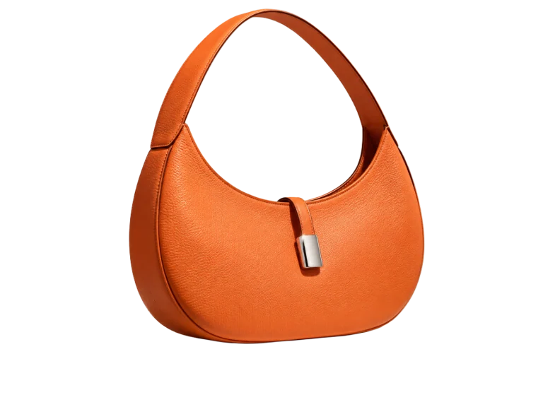 Sculptural orange leather handbag on an ivory pedestal, compared with the same bag isolated — Background removed